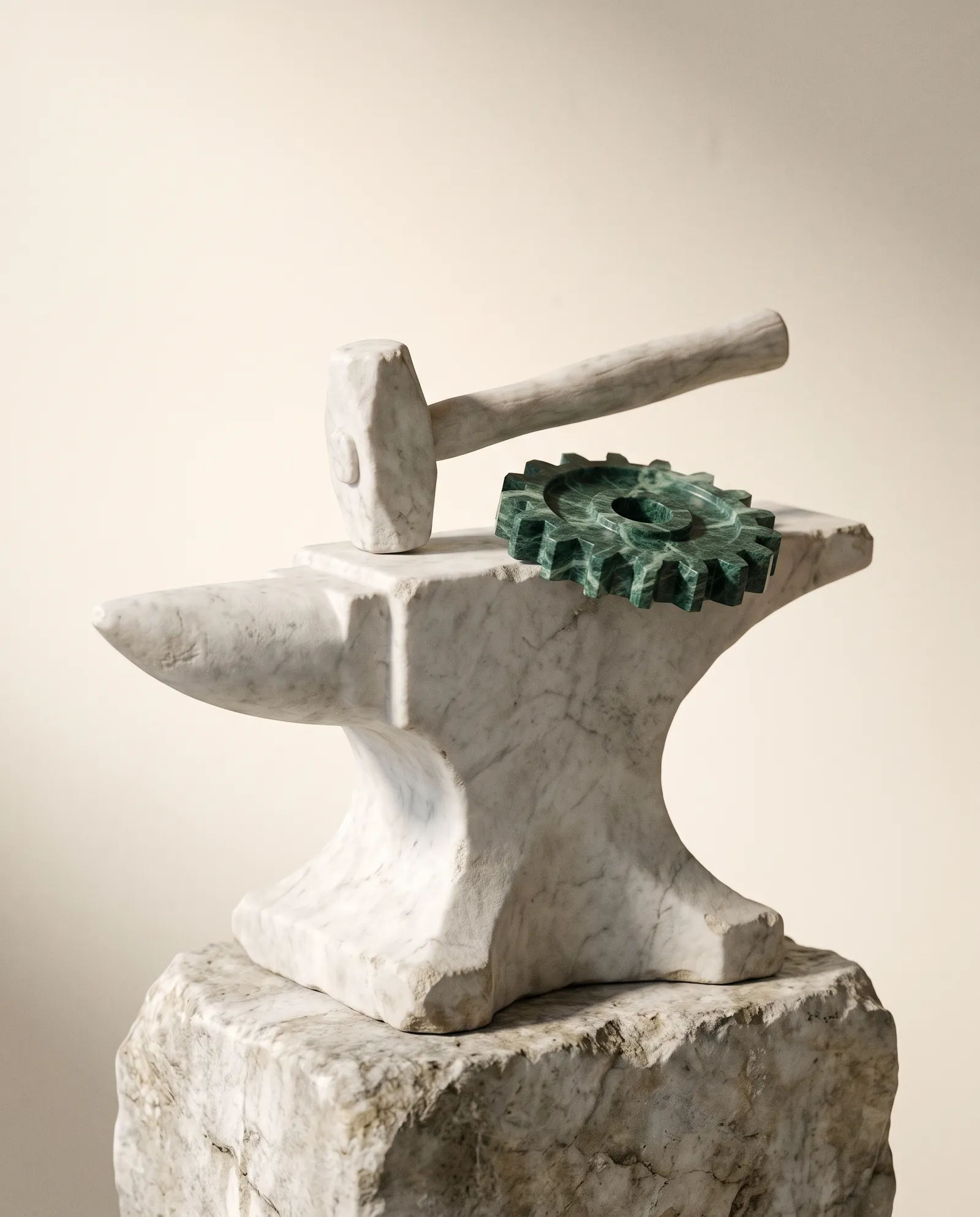 A marble anvil and hammer, with a gear wheel of green marble beside them.